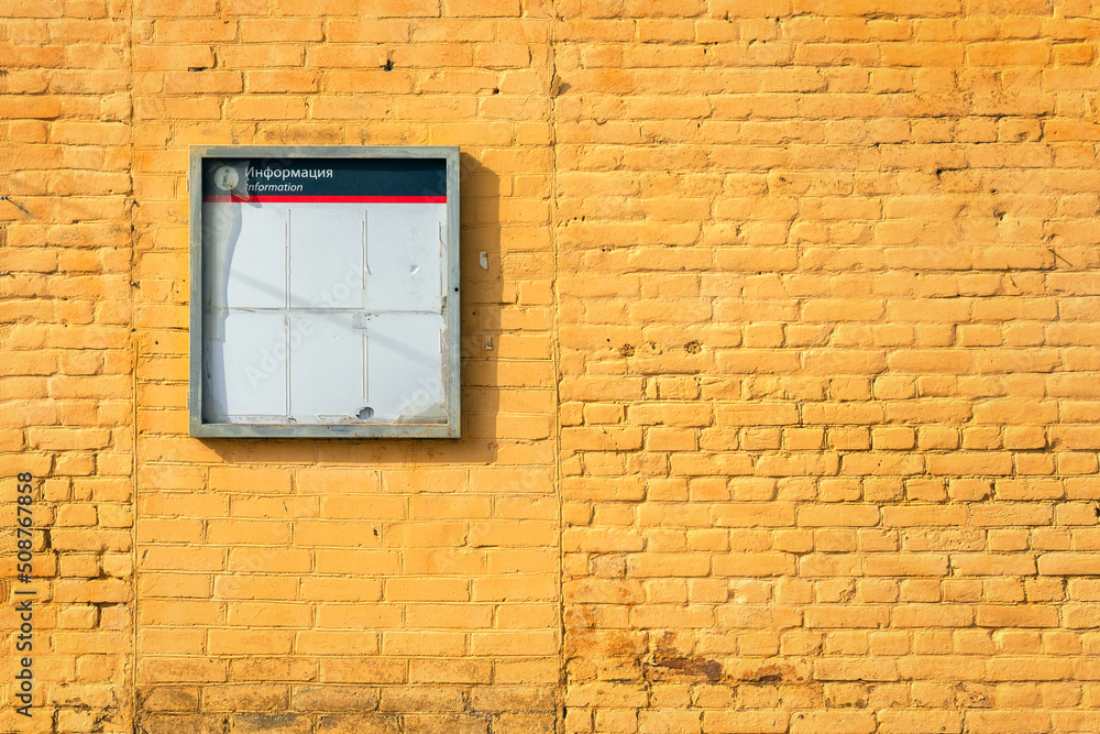 A bright yellow brick wall. The wall of the building is made of brick, painted yellow. Information stand with the inscription: 