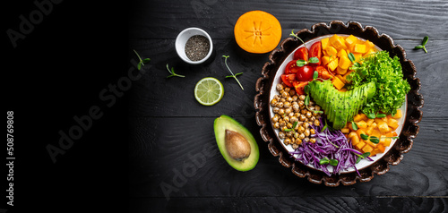 Healthy salad with avocado, tomato, red cabbage, chickpea, fresh lettuce salad, pumpkin, persimmon. Vegetarian menu, Long banner format. top view