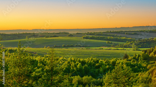 Summer landscape sunset sky over green fields and forests