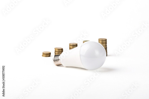 Energy saving light bulb. LED light bulb and coins. Electricity prices.