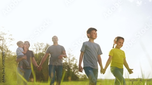 people in the park. happy family kid walk at sunset. mom dad and daughter baby walk holding hands in the park. happy family kid concept. parents and fun children. people walk in a dream green park