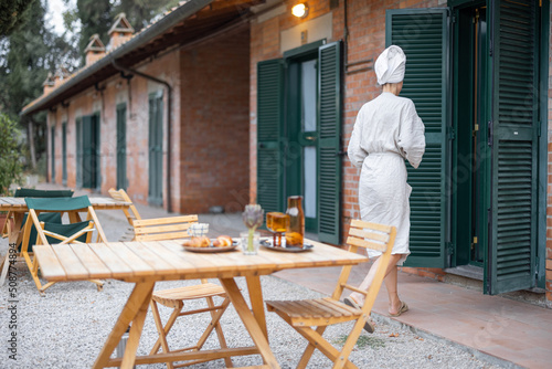 Woman carrying food to table for breakfast during resting in hotel at morning time. Concept of weekend, tourism and vacation. Young caucasian woman wearing bathrobe and wrapped bath towel on head