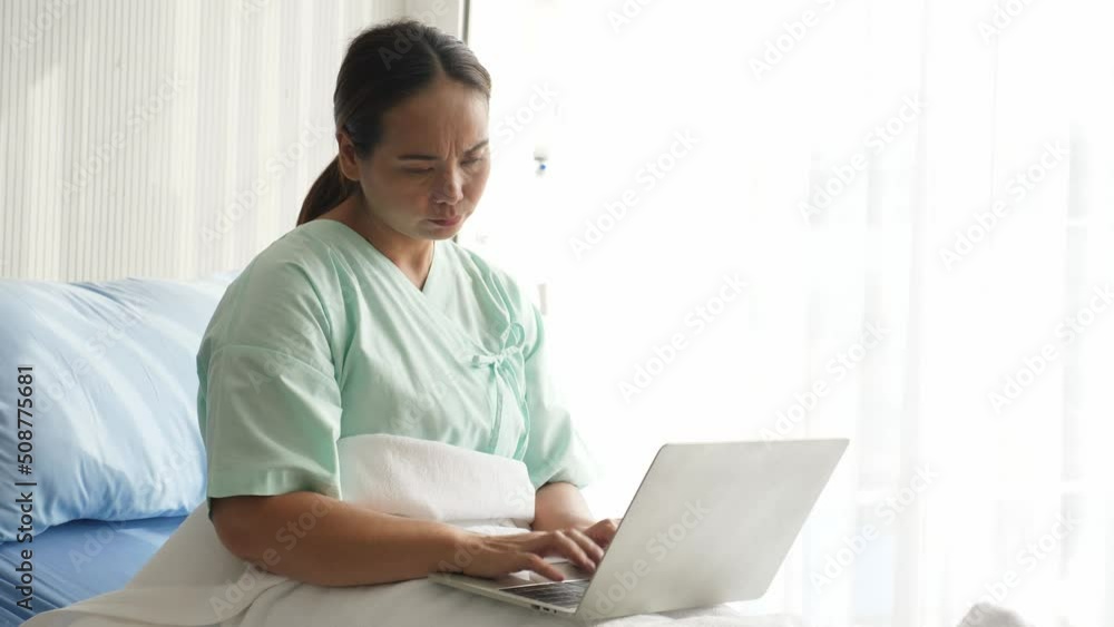 Busy Asian female patient sitting on bed, using laptop computer, typing, working while being sick, having stress and headache, then stop working and lying on bed to rest. Workaholic and health concept Busy Asian female patient sitting on bed, using laptop computer, typing, working while being sick, having stress and headache, then stop working and lying on bed to rest. Workaholic and health concept