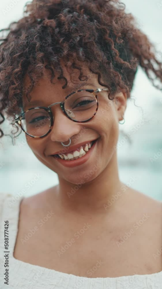 VERTICAL VIDEO: Closeup portrait of a young woman in glasses stands in the seaport and poses for the camera. Close-up portrait of happy girl on urban background. Camera zooming VERTICAL VIDEO: Closeup portrait of a young woman in glasses stands in the seaport and poses for the camera. Close-up portrait of happy girl on urban background. Camera zooming