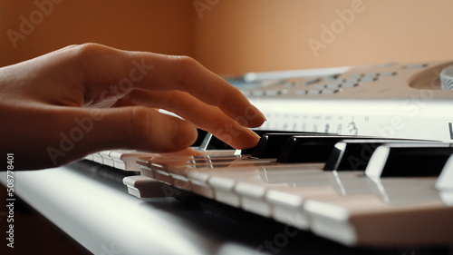 Female hand presses the keys of a synthesizer, selective focus, side view