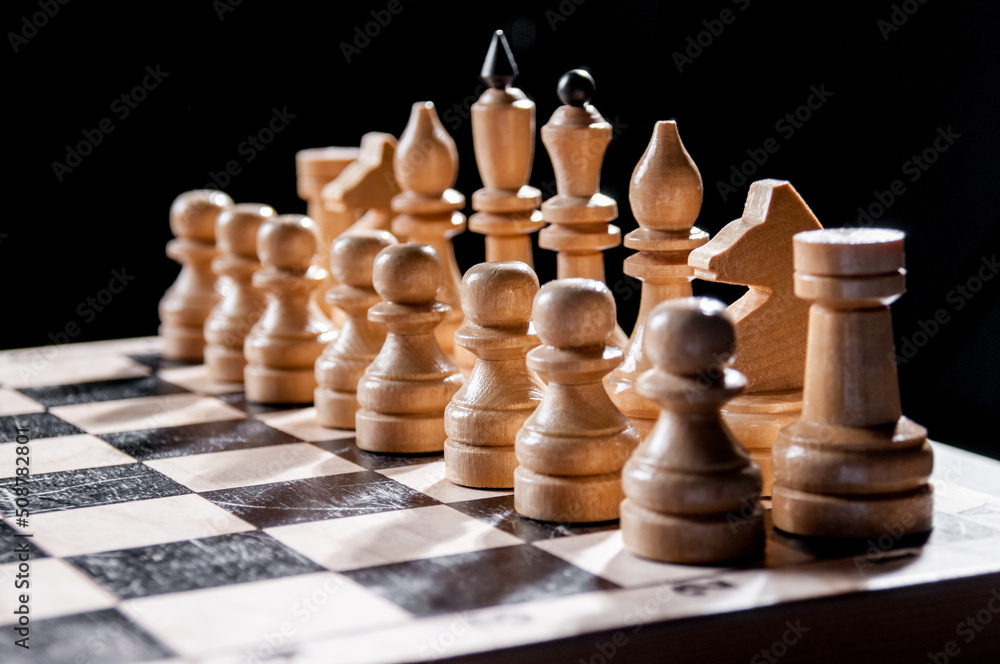 White chess pieces on a chessboard on a black background, board game White chess pieces on a chessboard on a black background, board game