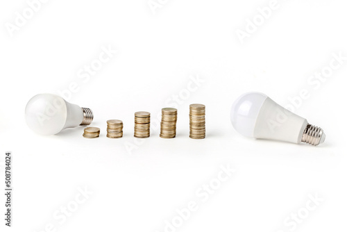 Energy saving light bulb. LED light bulb and coins. Electricity prices.