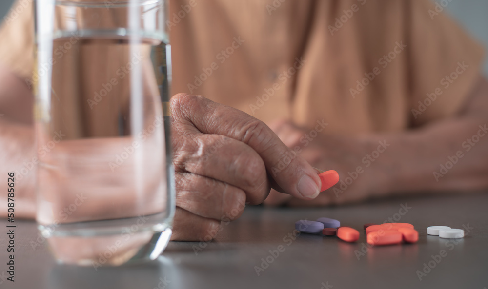 The old woman picked up a multicolored pill that was placed on the table The old woman picked up a multicolored pill that was placed on the table