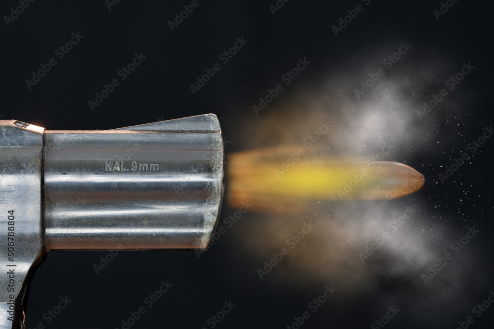 The deadly bullet flies out of the barrel of a revolver. A modern