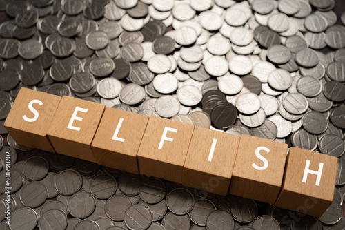 自己中心的のイメージ｜「SELFISH」と書かれた積み木とコイン photo