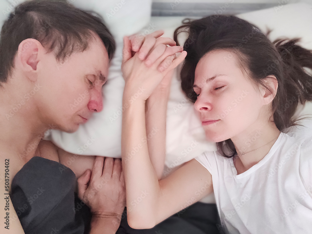 Loving married couple sleeping and holding hands - eyes closed Loving married couple sleeping and holding hands - eyes closed