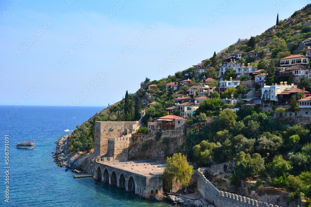 coastline with ancient fortress, typical turkish houses and green trees in summer