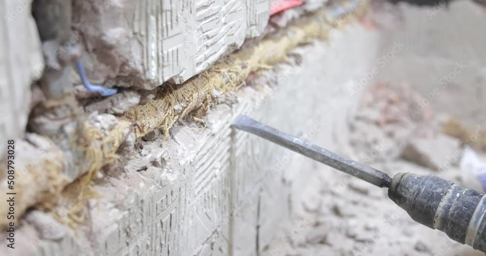 Plumber using a jackhammer to drill into wall, professional worker