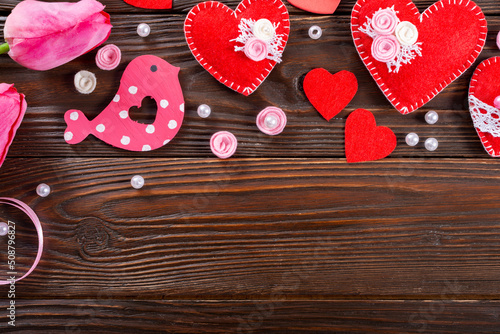 Sewed handmade fabric hearts tulips and ribbon for valentine day on dark wooden background with copy space