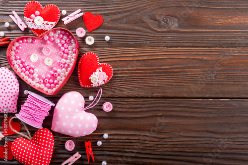 DIY Valentine hearts laundry pins and sewing spool on wooden table flat lay with copy-space