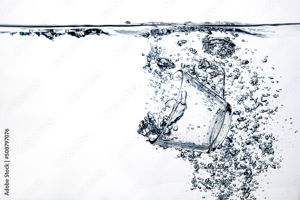 transparent glass dropped into the water on a white background
