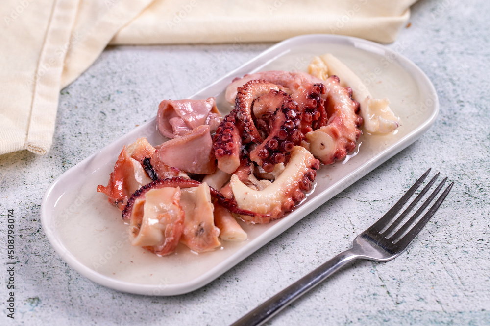 Octopus salad. Mediterranean cuisine delicacies. Octopus arms with olive oil on stone background. Close-up