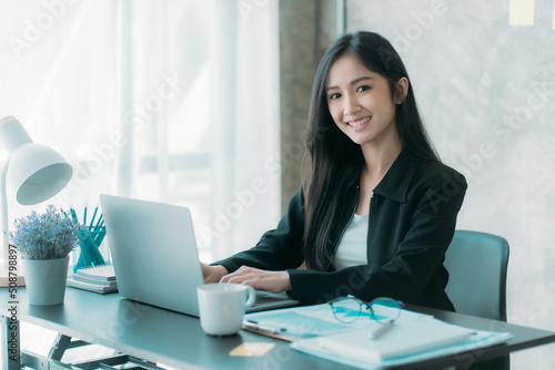 Businesswoman or accountant using the phone to check business information. Accounting Documents and Laptop Computer at Office Business Ideas