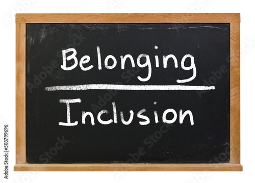 Belonging over inclusion written in white chalk on a black chalkboard isolated on white