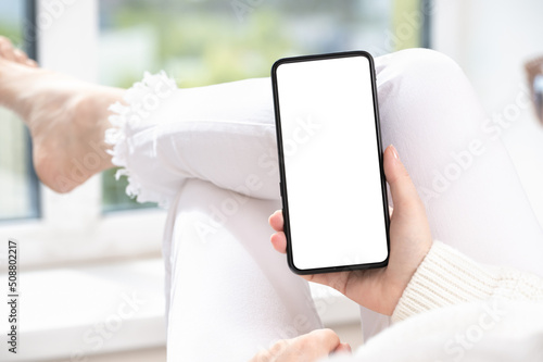 woman hand holding black cell phone smartphone with blank white screen and modern frame less design. cell mobile phone blank white screen mockup photo