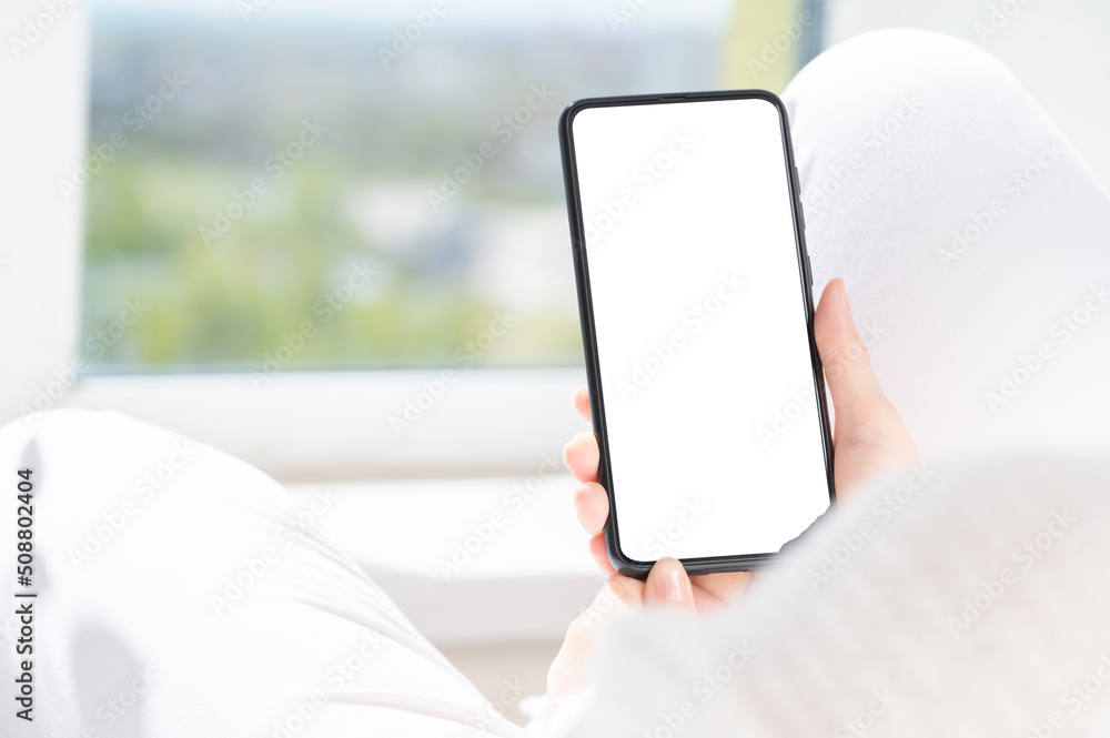 Cropped shot view of woman hands holding smart phone with blank copy space screen for text message or information content,. female reading text message on cell telephone at home