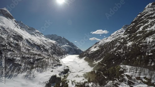 Lake of a frozen dam between snow-capped mountains