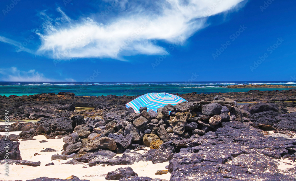 El Cotillo - Faro del Toston: One single isolated blue umbrella between wind shelter black volcanic rocks on beach with ocean horizon, north Fuerteventura
