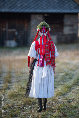 Woman dressed in traditional folk costume. Slovak costume in autumn nature. Old country cottage in the background. Details of Slovak costume from Detva and Hrinova