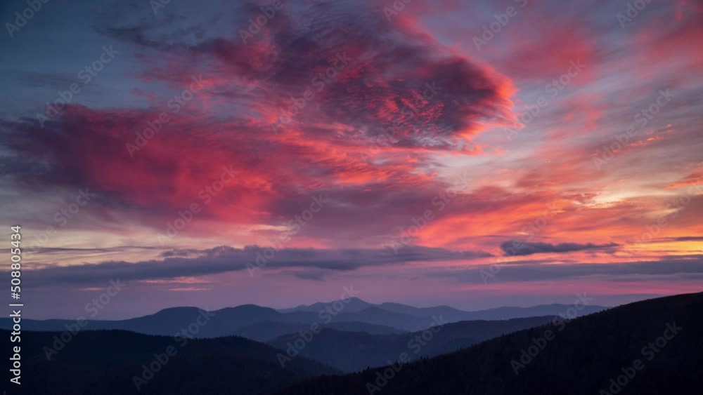 Time lapse epic pink fading to blue sunset in mountain valley. Dramatic clouds moving slowly over layers of ridge silhouettes. Relaxing landscape background Time lapse epic pink fading to blue sunset in mountain valley. Dramatic clouds moving slowly over layers of ridge silhouettes. Relaxing landscape background