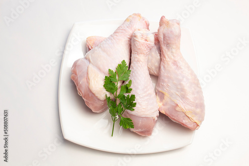 raw chicken legs in a plate on a white background