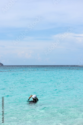 Asian children on black swimming suite with white cap swimming in turquoise Andaman sea at Koh Similan or Similan Island, Pangnga, Southern Thailand. Summer vacation travel.