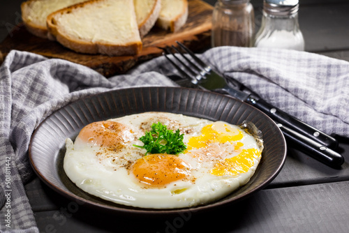 Fried eggs and bread for breakfast on a gray background.