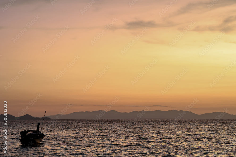 Stunning silhouette wooden fishing boats in Andaman sea during golden sunrise at Koh Lipe or Lipe island, Satun, Southern Thailand. Summer time or vacation travel concept.