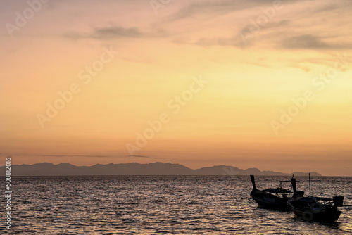 Stunning silhouette wooden fishing boats in Andaman sea during golden sunrise at Koh Lipe or Lipe island  Satun  Southern Thailand. Summer time or vacation travel concept.