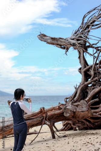 Asian woman use smartphone taking sea view and roadside photos in southern Thailand. Travel vacation concept.	