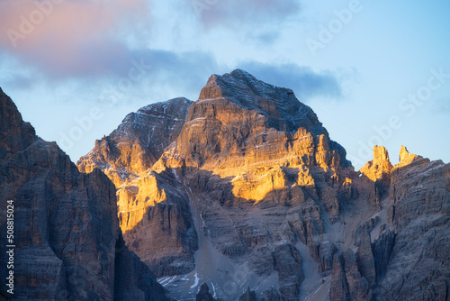 High rocks during sunset. Dolomite Alps  Italy. Mountains and cloudy skies. View of mountains and cliffs. Natural mountain scenery. Photography as a background for travel.