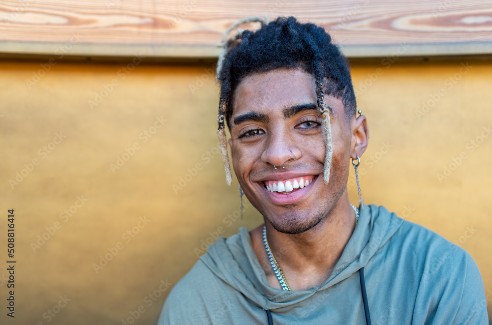 Obraz premium close up portrait of alternative black man hanging out chilling and smiling standing isolated against modern wood background wall. happy people smiling at camera relaxing outdoors. lifestyle concept