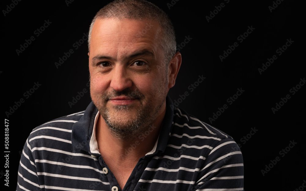 Smiling man with one eyebrow raised on a black background with copy space