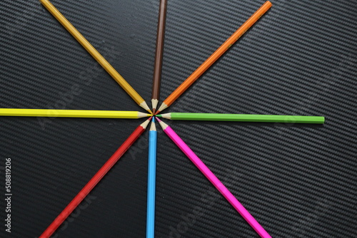 Color pencils on black table in star shape facing each other