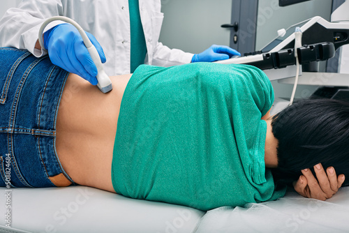Ultrasound of kidneys. Woman patient during ultrasound examination in medical clinic lying on side, view from back photo
