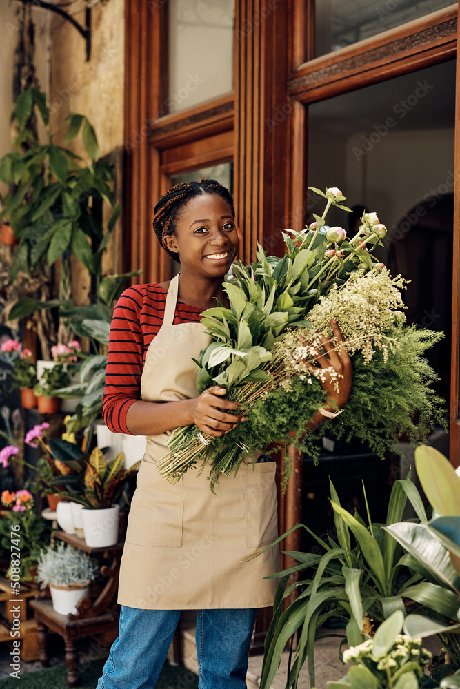 Happy black flower shop owner in front of her store looking at camera. Happy black flower shop owner in front of her store looking at camera.