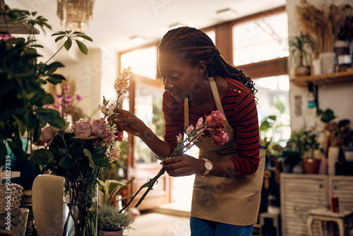 Принти на полотні Creative black florist arranging flowers while working at her flower shop