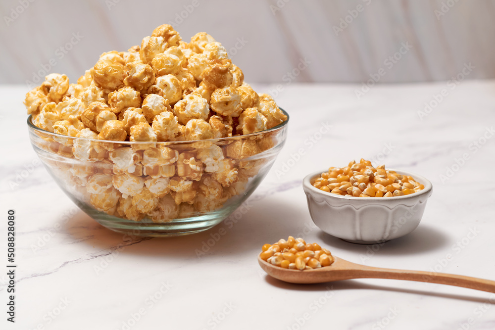 Bowl with delicious caramel popcorn on white table Bowl with delicious caramel popcorn on white table