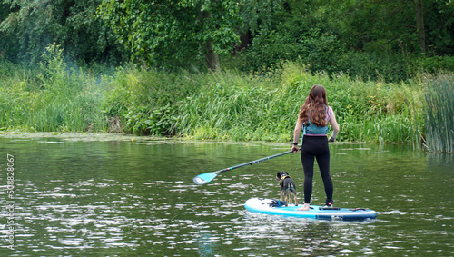 Vászonkép Girl on  Stand up Paddle Board with Dog on river.