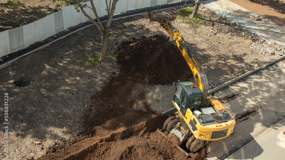 yellow excavator digs a hole at a construction site, top view yellow excavator digs a hole at a construction site, top view