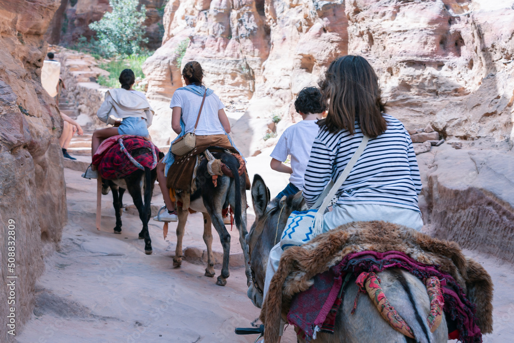 Tourist using a Bedouin donkey for transport in Petra Jordan. Descends stairs next to other tourists walking