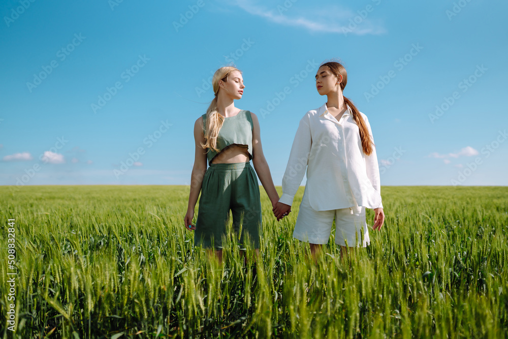 Two Beautiful woman in the green field. Nature, vacation, relax and lifestyle. Summer landscape. Fashion, style concept. Two Beautiful woman in the green field. Nature, vacation, relax and lifestyle. Summer landscape. Fashion, style concept.