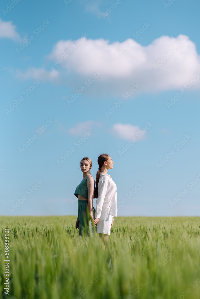 Two Beautiful woman in the green field. Nature, vacation, relax and lifestyle. Summer landscape. Fashion, style concept. Two Beautiful woman in the green field. Nature, vacation, relax and lifestyle. Summer landscape. Fashion, style concept.