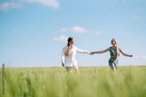 Two Beautiful woman in the green field. Nature, vacation, relax and lifestyle. Summer landscape. Fashion, style concept.
