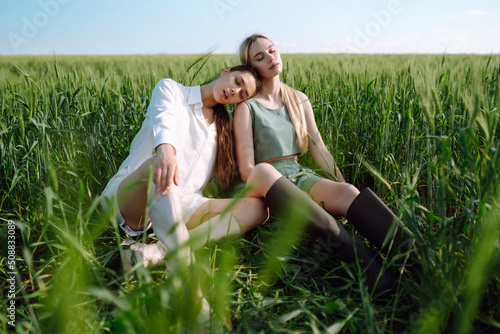 Two Beautiful woman in the green field. Nature, vacation, relax and lifestyle. Summer landscape. Fashion, style concept.